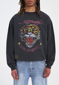 Felpa nera con grafica di tigre, accenti rossi e gialli. Logo "Ed Hardy" sopra, "Los Angeles" sotto in rosa. Tessuto morbido, vestibilità comoda.