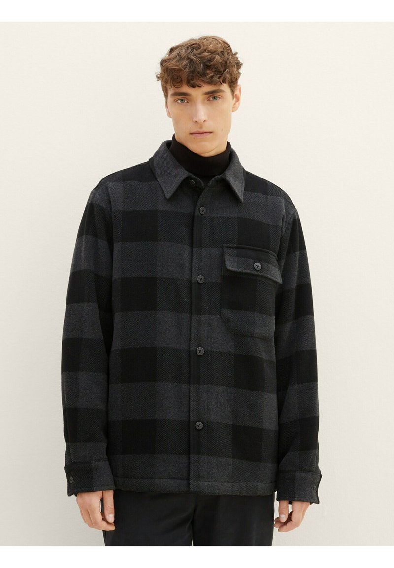 Schwarz-graues kariertes Hemd mit Knopfverschluss und Kragen, ausgestattet mit einer Brusttasche und langen Ärmeln. Hergestellt aus einem strukturierten Stoff.