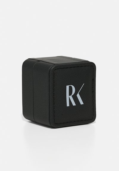 Crna kožna kutija u obliku kocke s teksturiranim površinom i vidljivim šavovima. Ima srebrni logo "RK" sprijeda.