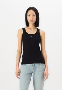 Svart ribbet tanktop med scoop-hals, brede skulderstropper og en liten logodetalj på brystet. Myk bomullsblandingsstoff.