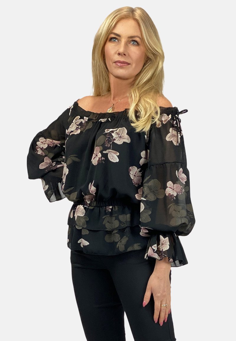 Czarna bluzka z odkrytymi ramionami, z kwiecistym nadrukiem, w kształcie dzwonu rękawami i falbaną na dole. Wykonana z lekkiego materiału o przezroczystej teksturze.