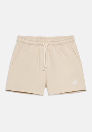 Shorts beige à taille élastique avec cordon de serrage, poches latérales et petit logo sur la cuisse gauche, posés à plat sur un fond blanc.
