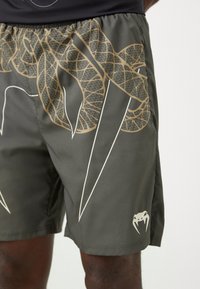 Bañadores verdes con un diseño de serpiente marrón y patrones geométricos. Confeccionados en una tela suave con una cinturilla elástica y un logo en el dobladillo.