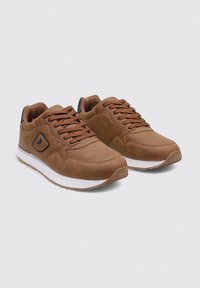 Zapatillas deportivas marrones hechas de material sintético con un acabado texturizado. Las características incluyen cordones, costuras tonales y una suela de goma blanca.