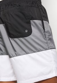 Färggranna badshorts med svarta, grå och vita paneler. Tillverkade av lättviktigt material, inkluderar en bakficka med tryckknappsstängning.