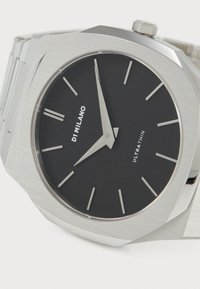 Montre en acier inoxydable avec un boîtier octogonal, un cadran noir, des index en argent et des aiguilles ; comporte le texte « D1 MILANO » et « ULTRA THIN ». 