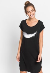 Abito t-shirt nero in cotone, con una grafica di piuma bianca sul petto, maniche corte arrotolate e spacchi laterali.
