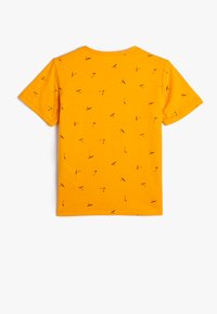 Gul t-shirt i bomull med korta ärmar och ett mönster av spridda svarta linjeteckningar. Rund halsringning och standardpassform.