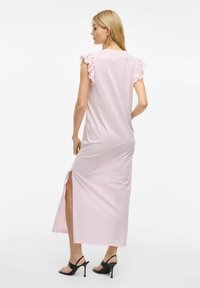 Różowa sukienka do kostek z falbaniastymi krótkimi rękawami, rozcięciem po boku i gładką teksturą, połączona z czarnymi butami na wysokim obcasie.