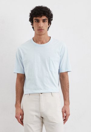 Lichtblauw T-shirt met korte mouwen van een zachte stof, met een ronde halslijn en een klein zakje aan de linkerkant.