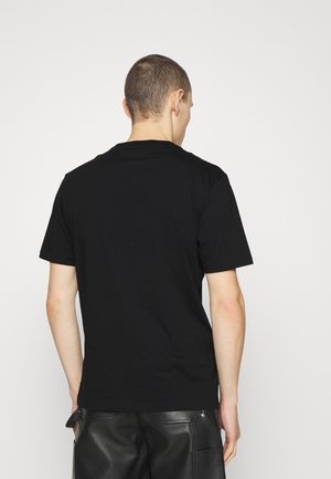 T-shirt noir en coton avec manches courtes et encolure ronde, présentant un design simple sans motifs ni logos.