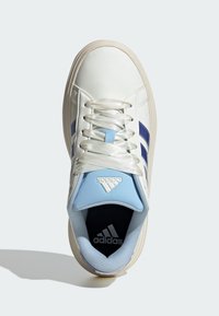 Bijela tenisica s plavim detaljima, s glatkim gornjim dijelom, zaobljenim vrhom i ravnim bijelim vezicama. Jezik teniske ima Adidasov logo u bijeloj boji.