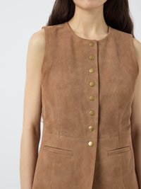Vest din suede maro, fără mâneci, cu gât rotund, cinci nasturi rotunzi aurii și buzunare laterale. Textură netedă cu un design ajustat.