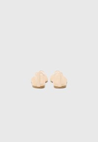 Nude-färgade lägenheter med en slät läderöverdel, öppen bakdesign och minimalistic form. Platta sulor i en tan-färg.
