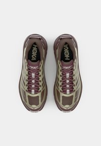 Scarpe Hoka One One, con tomaia in rete marrone e oliva, accenti marroni, punta arrotondata, lacci visibili e design della suola ammortizzata.