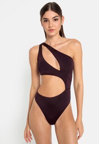 Maillot de bain violet à une épaule avec des détails découpés, un design sans couture et un aspect métallique. La coupe haute met en valeur la silhouette.