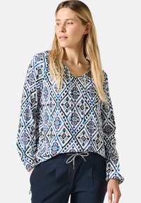 Leichte Bluse mit einem geometrischen Muster in Blau, Schwarz und Weiß. Lange Ärmel mit elastischen Manschetten, V-Ausschnitt mit Kordelzug-Detail.