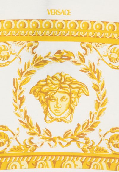 Złota głowa Meduzy otoczona wieńcem laurowym i ozdobnymi wzorami barokowymi na białym tle z żółtym logo "VERSACE" powyżej.
