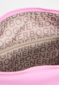 Roza torbica z zadrgo, odprta, da pokaže bež podlogo z ponovljenim napisom "BOGNER" in notranjim žepom z zadrgo.