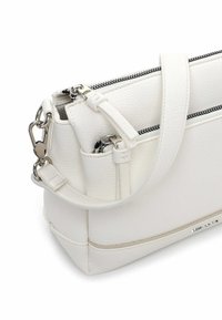 Biała skórzana torebka na ramię o fakturowanej powierzchni, srebrnej biżuterii, podwójnych zamkach błyskawicznych i odpinanym pasku. Kwadratowy kształt z minimalistycznym designem.