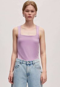 Lila tanktop met een vierkante halslijn en brede schouderbanden, gecombineerd met lichtblauwe, hoge taille spijkerbroeken met een relaxte fit en klassieke zakken.