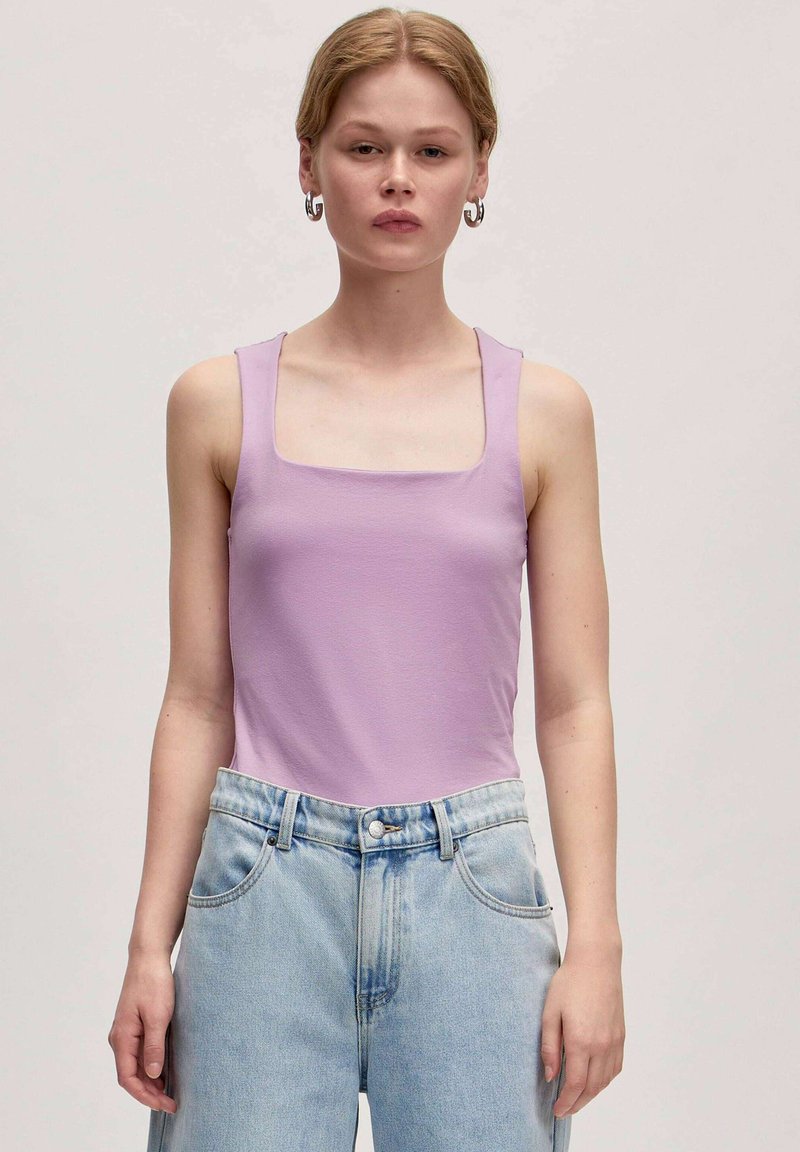 Lila tanktop met een vierkante halslijn en brede schouderbanden, gecombineerd met lichtblauwe, hoge taille spijkerbroeken met een relaxte fit en klassieke zakken.