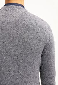 Pull gris en tricot avec une finition texturée, doté d'un col rond et de détails contrastants bleu marine au niveau du col.