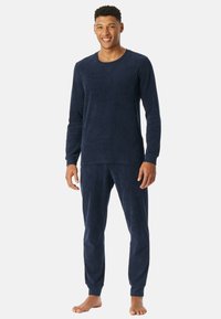 Mørkeblå fleece pyjamas sæt bestående af en langærmet skjorte og tætsiddende bukser med ribbede manchetter, der giver en blød tekstur og varme.