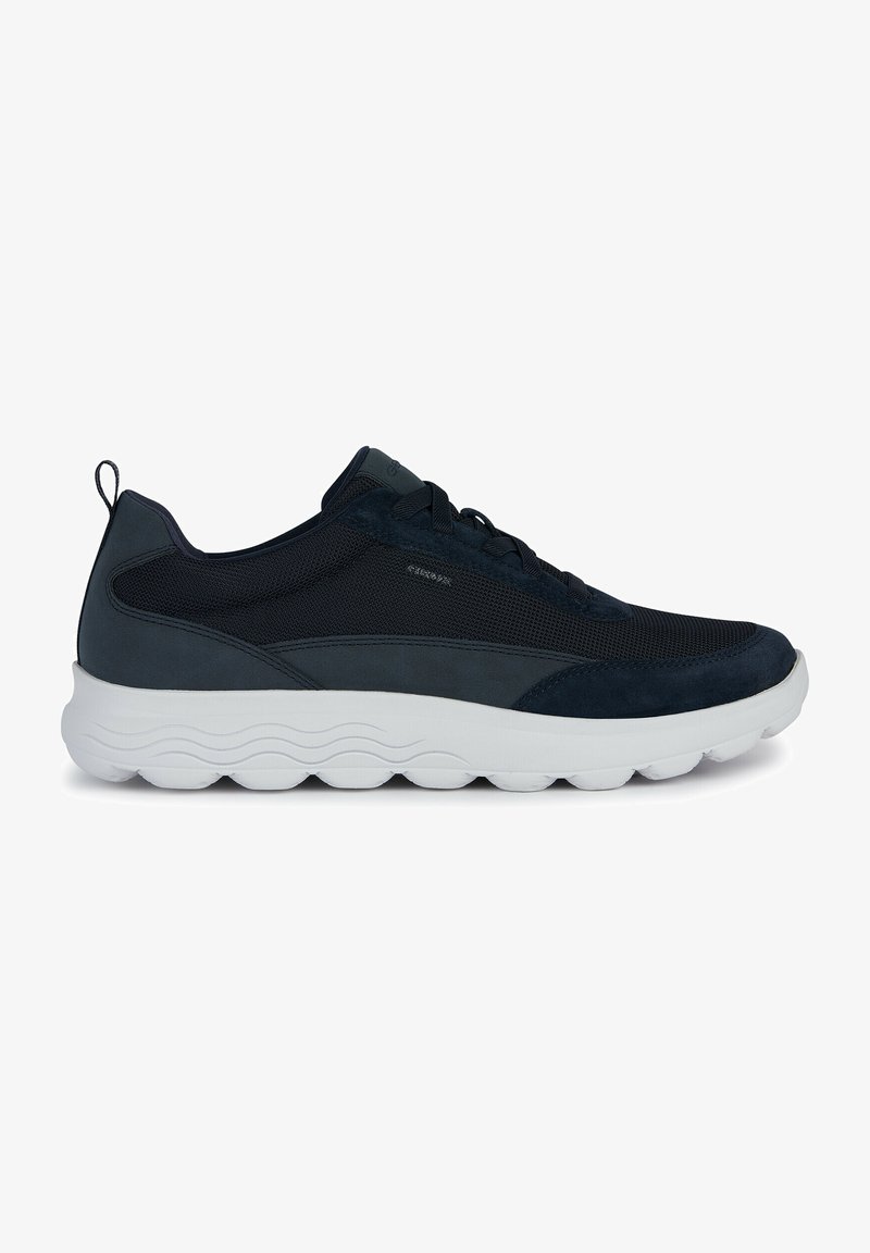 Chaussures de sport bleu marine en mesh et en daim, avec un dessus texturé, un bout rond et une semelle en caoutchouc blanc ornée de motifs en vagues.