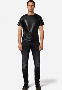 Schwarzes Lederoberteil mit kurzen Ärmeln und rundem Ausschnitt, kombiniert mit dunklen Jeans und schwarzen Lederstiefeln. Einfaches, elegantes Design.