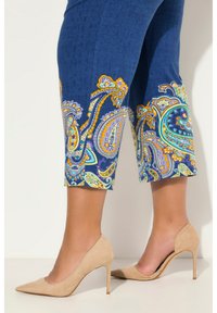 Blauwe capri-broeken met een levendig paisleypatroon aan de onderkant, gemaakt van textuurstof. Gecombineerd met naakte hakken.