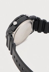 Mustast silikoonist käekell tekstureeritud rihmaga, ümmarguse korpusega, kahekordsete hõbedaste nuppudega ja roostevabast terasest tagaküljega.