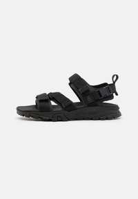Svart sporty sandaler med justerbare reimer, teksturert fotbed, gummisåle og et slitesterkt design som er egnet for utendørsbruk.