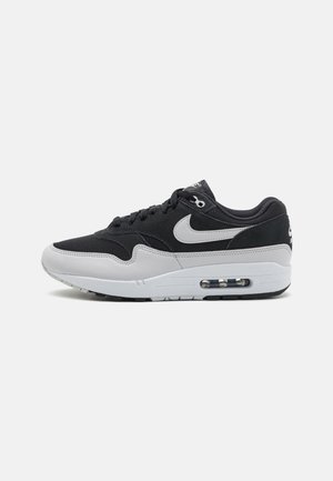 Baskets Nike Air Max noir et gris avec coussin d'air visible dans la semelle, tige en mesh et cuir, et logo Nike swoosh blanc sur le côté.