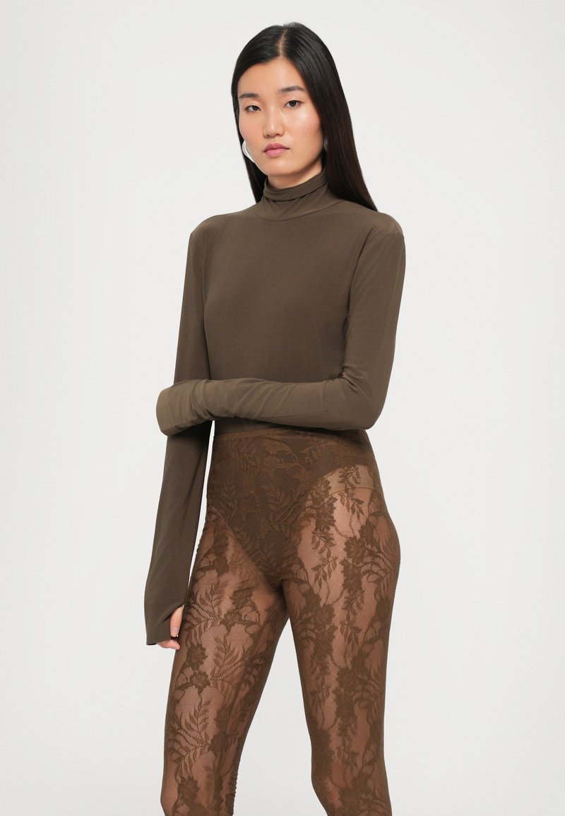 Braunes Longsleeve-Oberteil mit hoher Ausschnittform, kombiniert mit durchsichtigen, braunen Spitzenleggings mit Blumendesign. Glatte Textur, figurbetontes Design und vollständige Abdeckung.