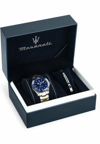 Maserati Uhren- und Armband-Set in einer navyblauen Box. Die Uhr verfügt über ein blaues Ziffernblatt und ein Armband aus Edelstahl in Silber und Gold. Das Samtfutter hebt die Gegenstände hervor.