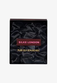 Boks som inneholder svarte, rene silkescrunchies med "Silke London"-merke i rosa og gull tekst på emballasjen.