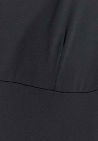 Tissu noir lisse avec une couture horizontale et un pli vertical créant une légère ombre.