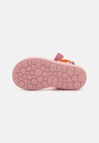 Rosa Gummisohlen mit strukturierten, kreisförmigen Mustern, ausgestattet mit einem kleinen orangefarbenen Riemen und einem Griff zum einfachen Befestigen.