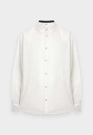 Chemise blanche à manches longues avec col classique et boutons beige, présentée sur un fond uni.