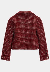 Veste en tweed rouge avec un motif tissé texturé, longueur courte et col à revers. Présente des poignets boutonnés et des accents métalliques subtils.