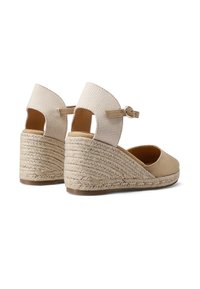 Scarpe con zeppa in espadrille beige, con tomaia in tessuto testurizzato, cinturino alla caviglia regolabile e dettagli in juta intrecciata sul tacco a zeppa.