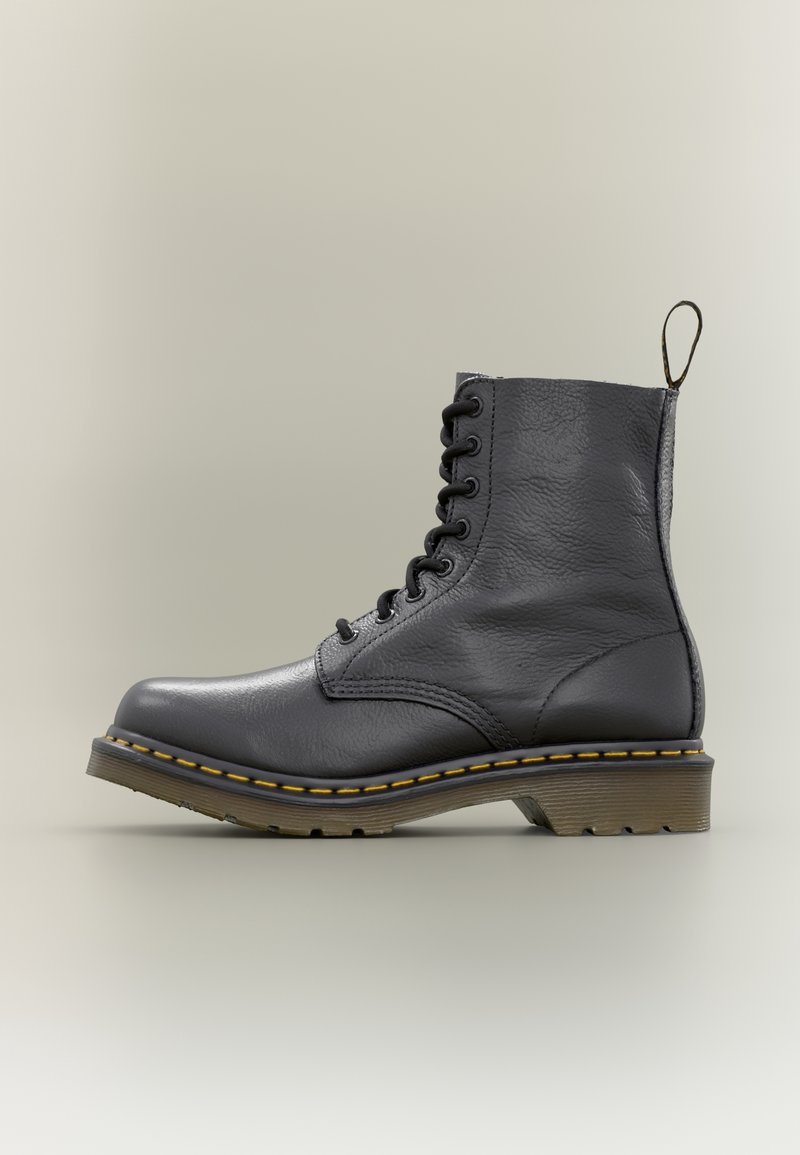 Bottine en cuir noir à lacets avec coutures jaunes et une languette de tirage sur un fond clair.