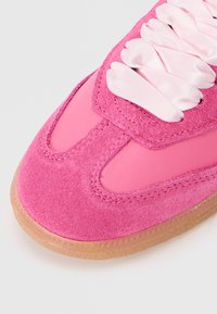 Roze tenisice s vupperom od velura, glatkim detaljima, satenastim vezicama i prozirnom gumenom potplatom za bolji grip. Prepoznatljiv dizajn zaobljenog vrha.