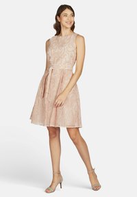 Rosa Spitzenkleid mit tailliertem Oberteil, ausgestelltem Rock und einem passenden Bindegürtel in der Taille. Der Stoff hat ein strukturiertes Blumenmuster.