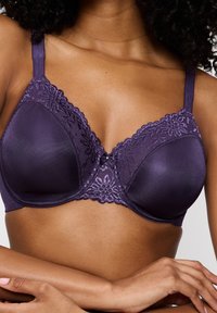 Violetti rintaliivit, joissa yläosassa pitsikoristelu, kupit sileää satiinipintaa ja säädettävät olkaimet. Keskellä pieni rusetti.