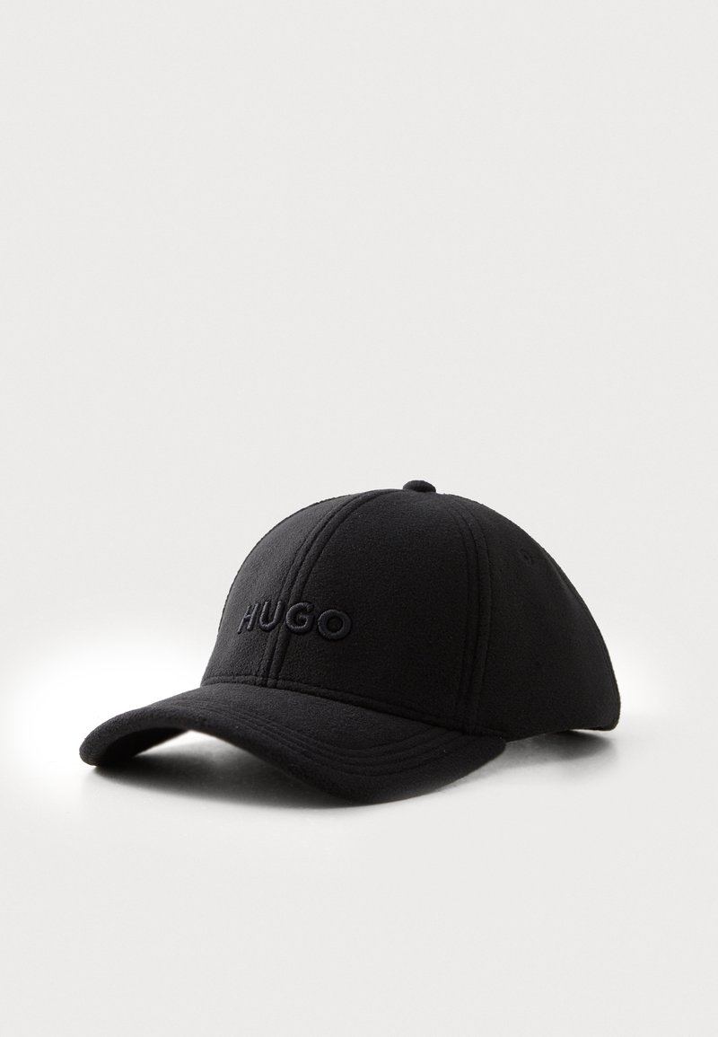 Casquette de baseball noire à visière courbée avec le logo brodé "HUGO" sur le panneau avant, présentée sur un fond clair uni.