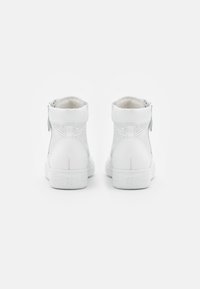 White high-top sneakers with perforated panels, a smooth toe cap, and a side zipper. Thick rubber sole with subtle branding on the heel.