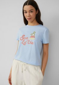 Lichtblauw katoenen t-shirt met een kleurrafiek en de tekst "Sea La Vie" en een gestileerd palmboom- en dessertmotief.