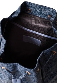 Borsa a sacco con coulisse in tessuto blu a fantasia, dotata di hardware in bronzo, con un interno nero liscio e un'etichetta cucita di lato.